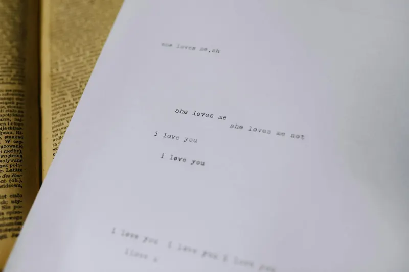 A close-up of typewritten text expressing love on white paper with an old book in the background.